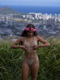 a woman in a bikini standing on top of a grassy hill