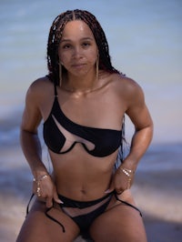 a woman in a black bikini posing on the beach