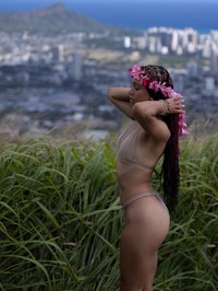 a woman in a bikini standing on top of a hill